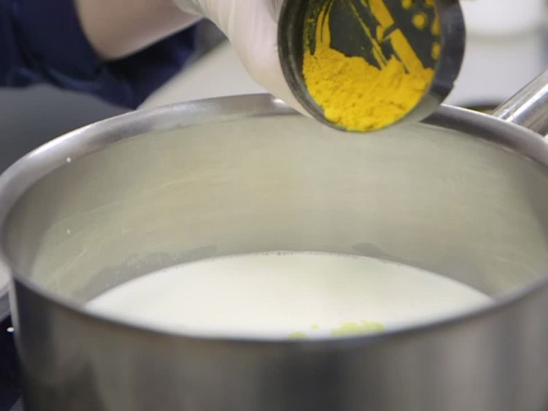 osoba dodaje kurkumu u mleko