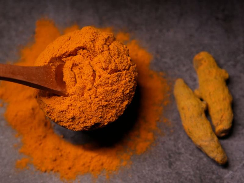 kurkuma u prahu u činiji i dva komada kurkume pored