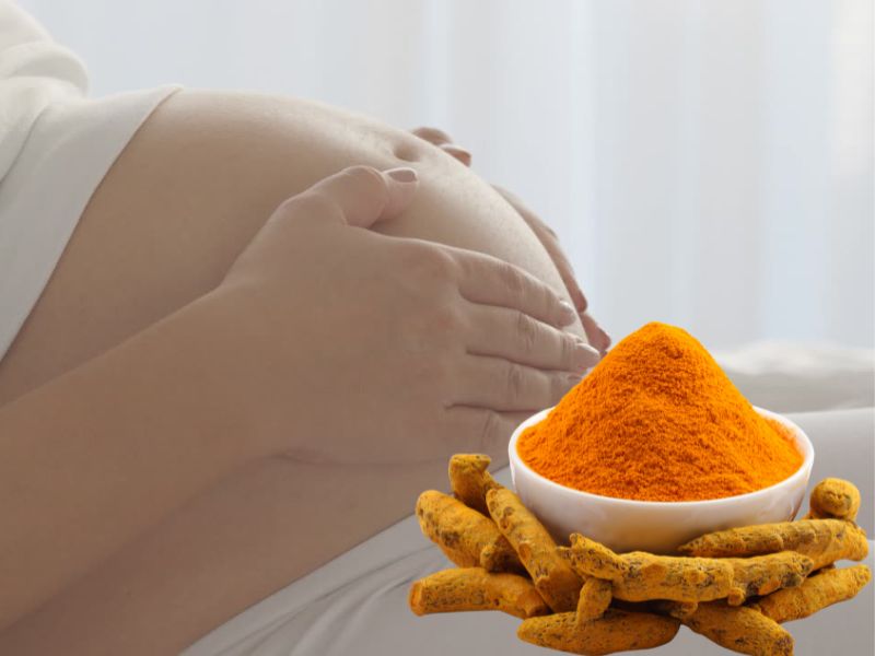 trudnica mazi svoj stomak, pored nje činija sa kurkumom u prahu i kurkuma